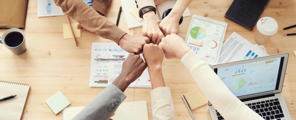 Diverse business team uniting over a strategy meeting with laptops and charts on the table, symbolizing collaboration between internal teams and external partners.