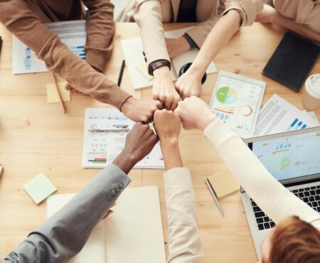 Diverse business team uniting over a strategy meeting with laptops and charts on the table, symbolizing collaboration between internal teams and external partners.